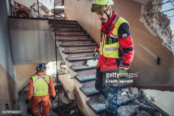 rescuer search trough ruins of building - emergencies and disasters stock pictures, royalty-free photos & images