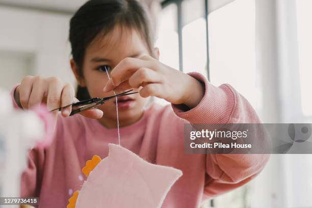 young mixed asian girl sewing felt at home, homeschooling concept - seam stockfoto's en -beelden