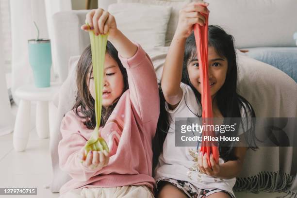 young multi-ethnic girls playing with homemade slime at home - glitschig stock-fotos und bilder