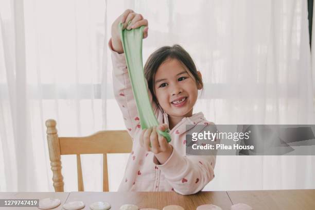 young mixed asian girl playing with homemade slime at home - limoso fotografías e imágenes de stock