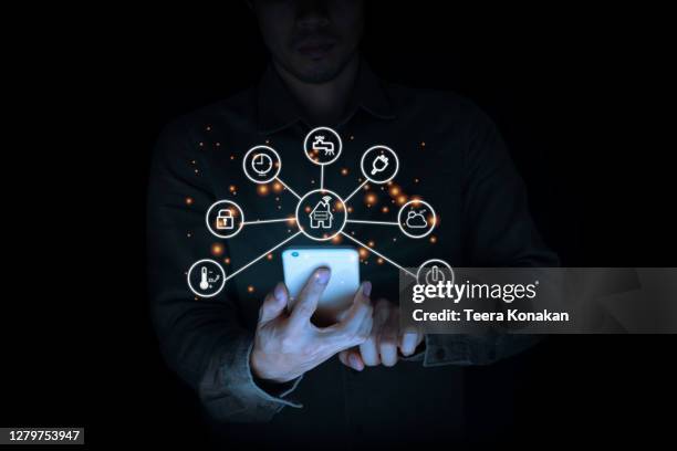 man using a smart home control system on a laptop with application that controls home electronics in a black background. smart home concept - ecosystem stock pictures, royalty-free photos & images
