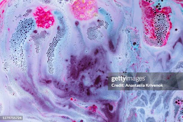 pink and blue bath bomb dissolving in the water. - bath bomb stock pictures, royalty-free photos & images