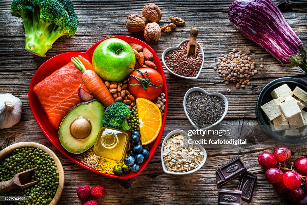 Alimentos saludables para reducir el colesterol y la inyección de cuidado del corazón en la mesa de madera