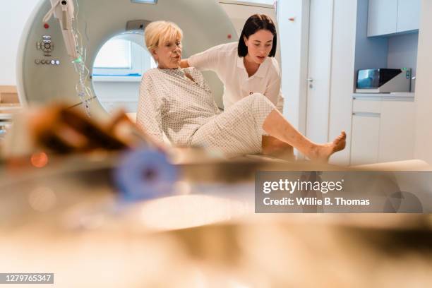 technician assisting mature woman get up from mri scanning bed - mri technician fotografías e imágenes de stock