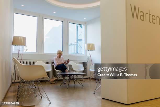 mature woman sitting in mri clinic waiting room - allgemeinarztpraxis stock-fotos und bilder