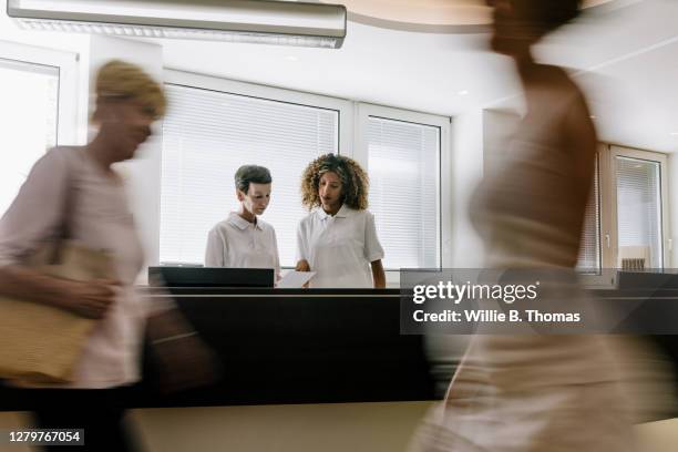 busy reception at mri clinic with patients walking by - busy hospital lobby stockfoto's en -beelden