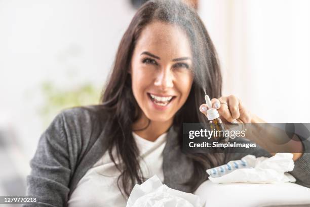 young woman sprays a nasal bottle spray into the air. - nasenspray stock-fotos und bilder