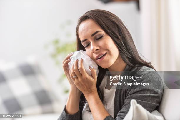 relief smile on a face of a woman holding bag of ice on her cheek. - rotten teeth from not brushing stockfoto's en -beelden