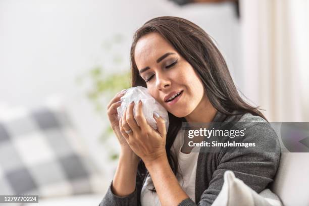 relief smile on a face of a woman holding bag of ice on her cheek. - rotten teeth from not brushing 個照片及圖片檔