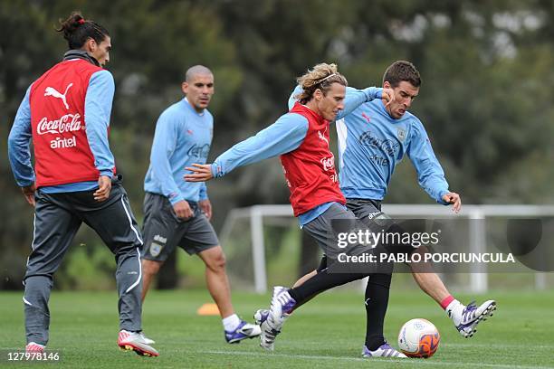 Uruguayan national footballers Andres Scotti and Diego Forlan vie for the ball as Walter Gargano and Martin Caceres look on, a training session in...