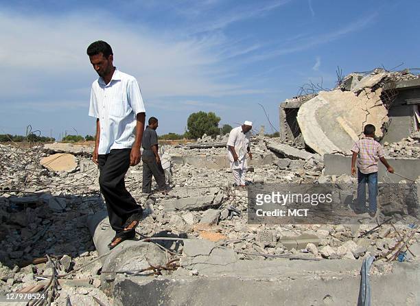Local residents pick through the rubble of homes that were flattened by NATO airstrikes on Aug. 8. NATO contends the area was a military target, but...