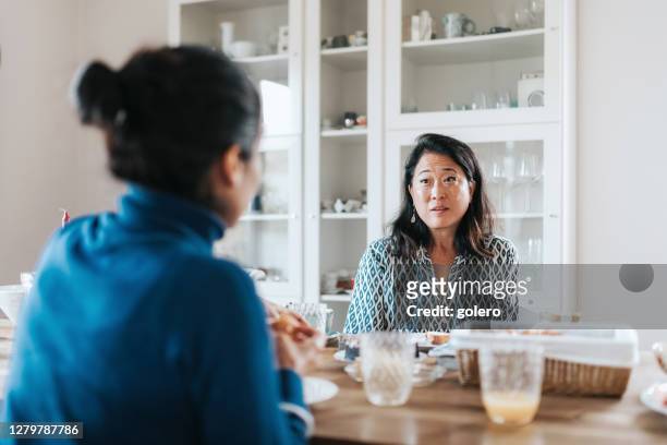 elegant woman at breakfast table listing to another woman - empathetic listening stock pictures, royalty-free photos & images