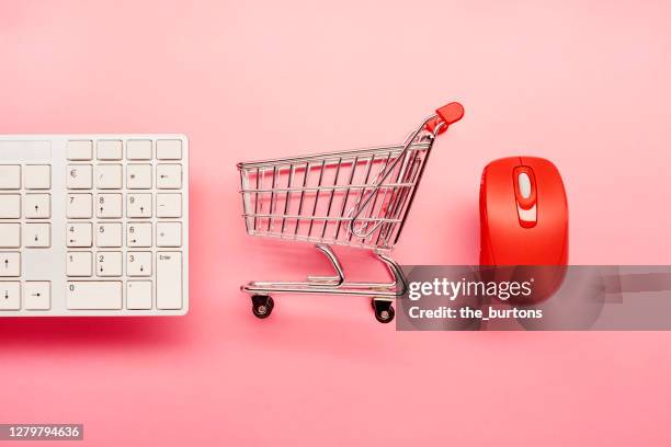 high angle view of a computer keyboard, small shopping cart and red computer mouse on pink background - mini mouse stock pictures, royalty-free photos & images