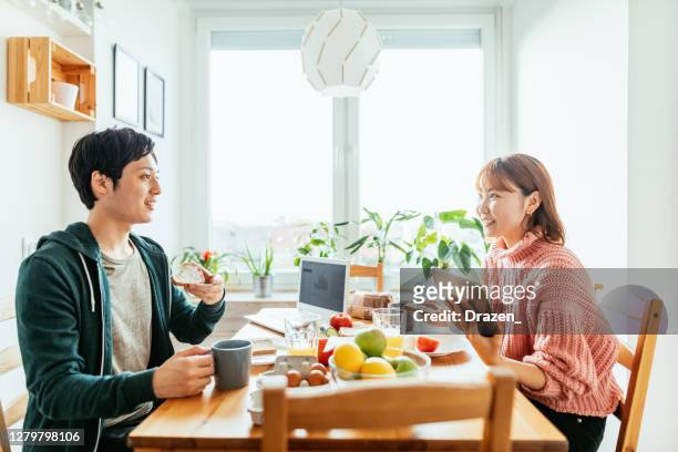 自宅で日本人カップル、キッチンで一緒に食事をし、リモートワークのための技術を使用 - 夫婦 ストックフォトと画像