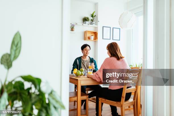 自宅で日本人カップル、台所で��一緒に食事をする、オレンジジュースを持つ男と笑顔 - 夫婦 ストックフォトと画像