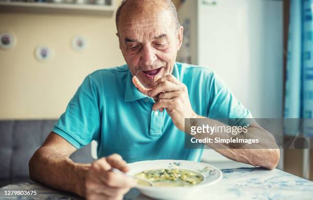 old man putting his denture on before the meal. - gebiss mensch zähne stock-fotos und bilder