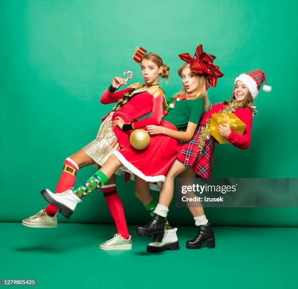 lustige weihnachten porträt von drei teenager-mädchen vor grünem hintergrund - christmas studio stock-fotos und bilder