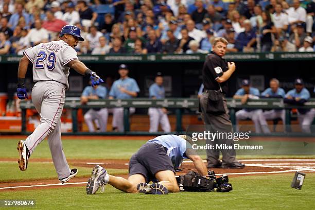 Adrian Beltre of the Texas Rangers rounds the bases and points at a TBS cameraman who falls on his way to video Beltre at home plate after Beltre...