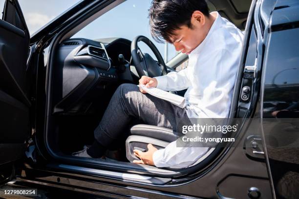 joven leyendo el libro de instrucciones y ajustando su asiento en un auto nuevo - manual fotografías e imágenes de stock
