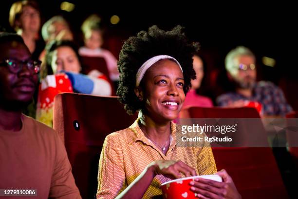 portrait of an african-american young woman enjoying with a friend at the cinema - film premiere stock pictures, royalty-free photos & images