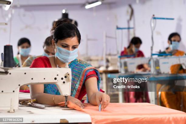 mujer india trabajadoras textiles con máscara protectora en la línea de producción - fábrica textil fotografías e imágenes de stock