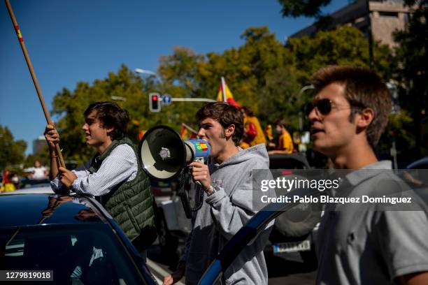 Demonstrator uses a speaker with far right wing VOX party logo during an in-vehicle protest against the Spanish government along Paseo de la...