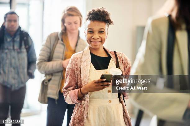 smiling young woman social distancing with others in a line - woman waiting in line stock pictures, royalty-free photos & images