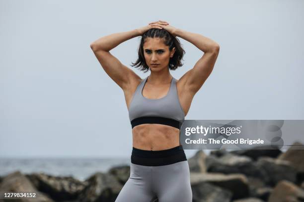 athletic woman standing on beach - sportlichkeit stock-fotos und bilder