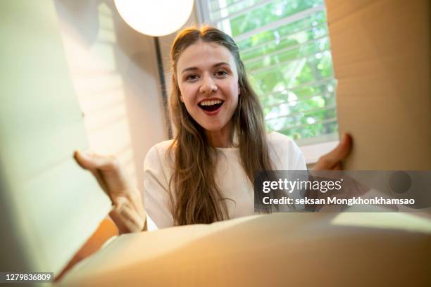 smiling woman opening a carton box - opening delivery stock pictures, royalty-free photos & images