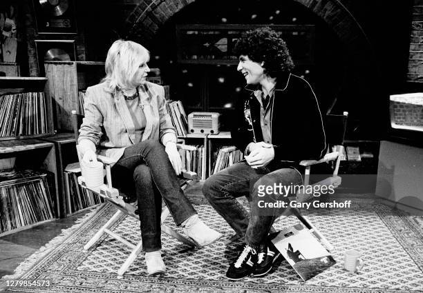 View of English Rock and Pop musician Christine McVie and American VJ Mark Goodman as they sit in director's chairs during an interview at MTV...