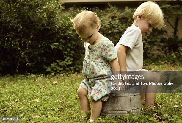 children sitting on pail - wash bowl stock-fotos und bilder