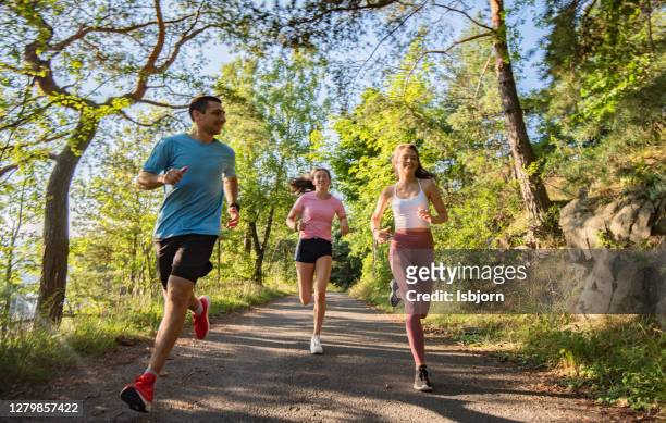 three young people jogging together in nature. - running stock pictures, royalty-free photos & images