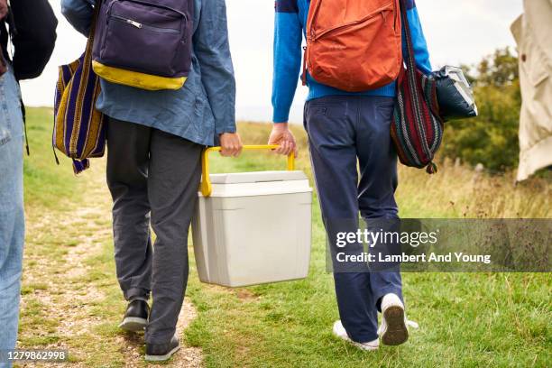 two boys holding a cool box walking to a camping spot - kühlbehälter stock-fotos und bilder