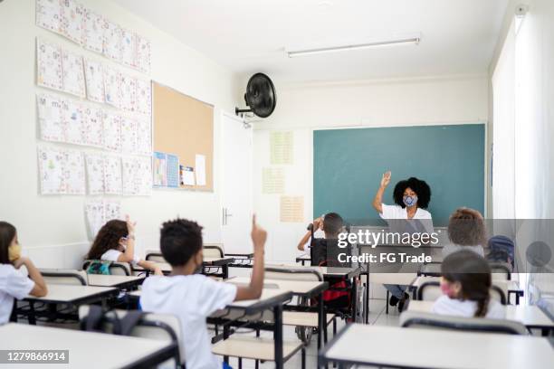 het onderwijs van de leraar in klaslokaal eerbiedigend sociaal distantiëren tussen studenten - social distancing classroom stockfoto's en -beelden