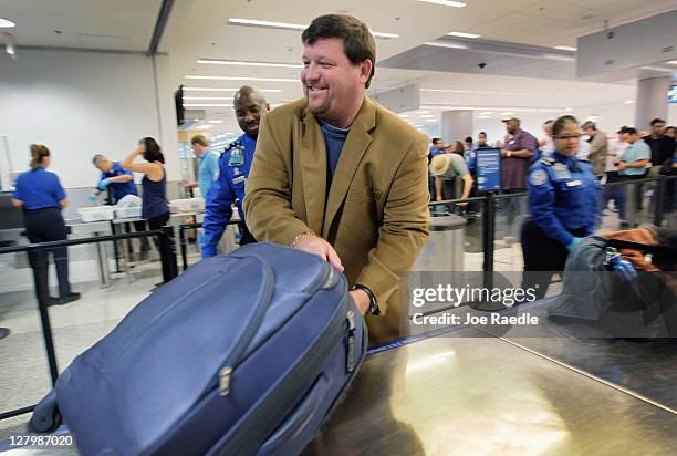 Ben Starrett places his bag on the table for security screening as he uses the new TSA PreCheck lane being implemented by the Transportation Security...