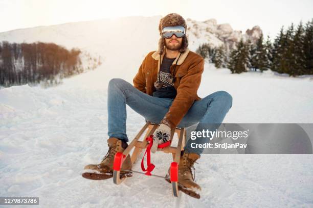 young man sledding in a mountain - hunters cap stock pictures, royalty-free photos & images