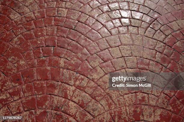 gloss rust red painted stencilled concrete in a scalloped cobblestone pattern - paving stone stock-fotos und bilder