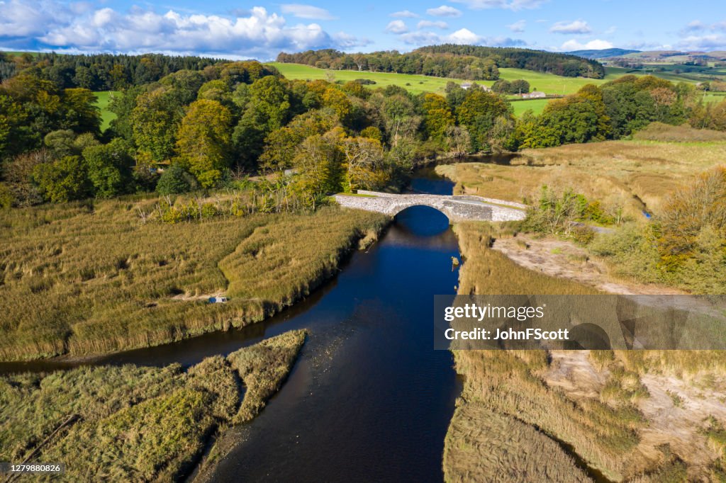 High angle view from a drone of an old stone bridge crossing a river in Dumfries and Galloway south west Scotland