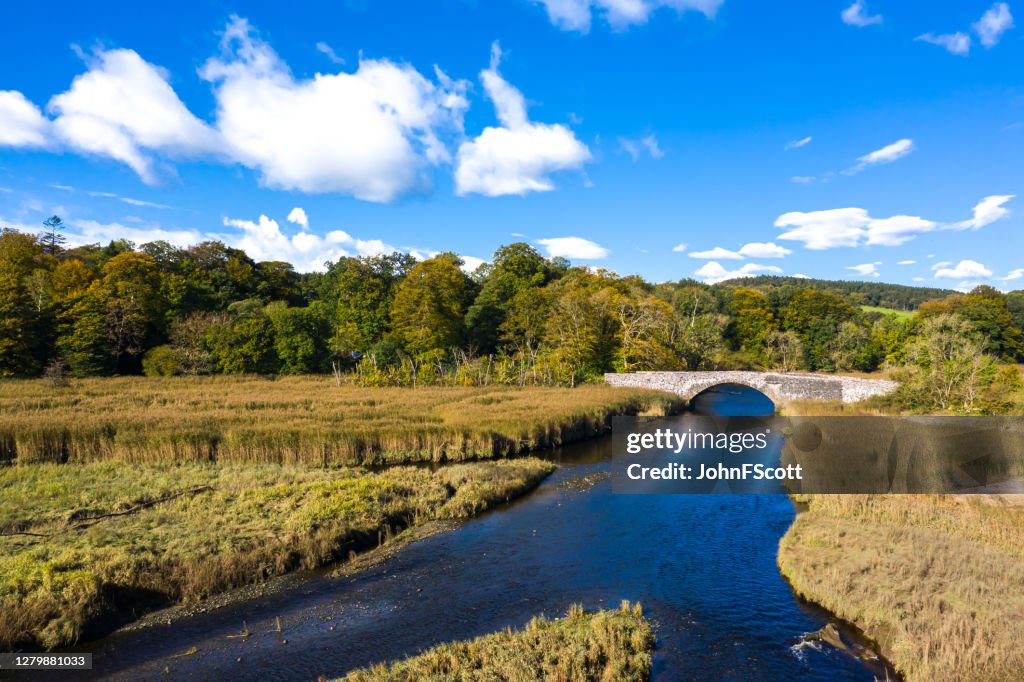 Vista ad alto angolo di un vecchio ponte di pietra che attraversa un piccolo fiume a Dumfries e Galloway, Scozia sud-occidentale