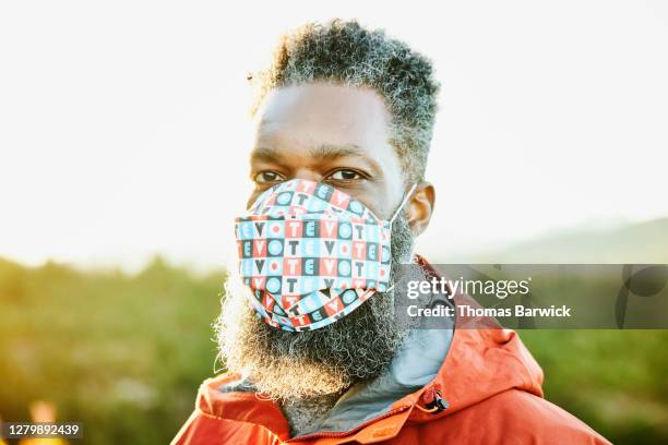 portrait of man wearing protective face mask that says vote - voting mask stock pictures, royalty-free photos & images