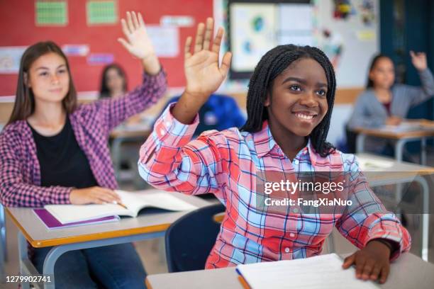 smiling diverse multi-cultural students raising hands in classroom - teacher taking attendance stock pictures, royalty-free photos & images