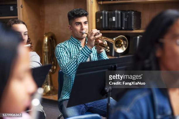学校のオーケストラバンドで友人とトランペットを練習する男性中東民族の学生 - トランペット奏者 ストックフォトと画像