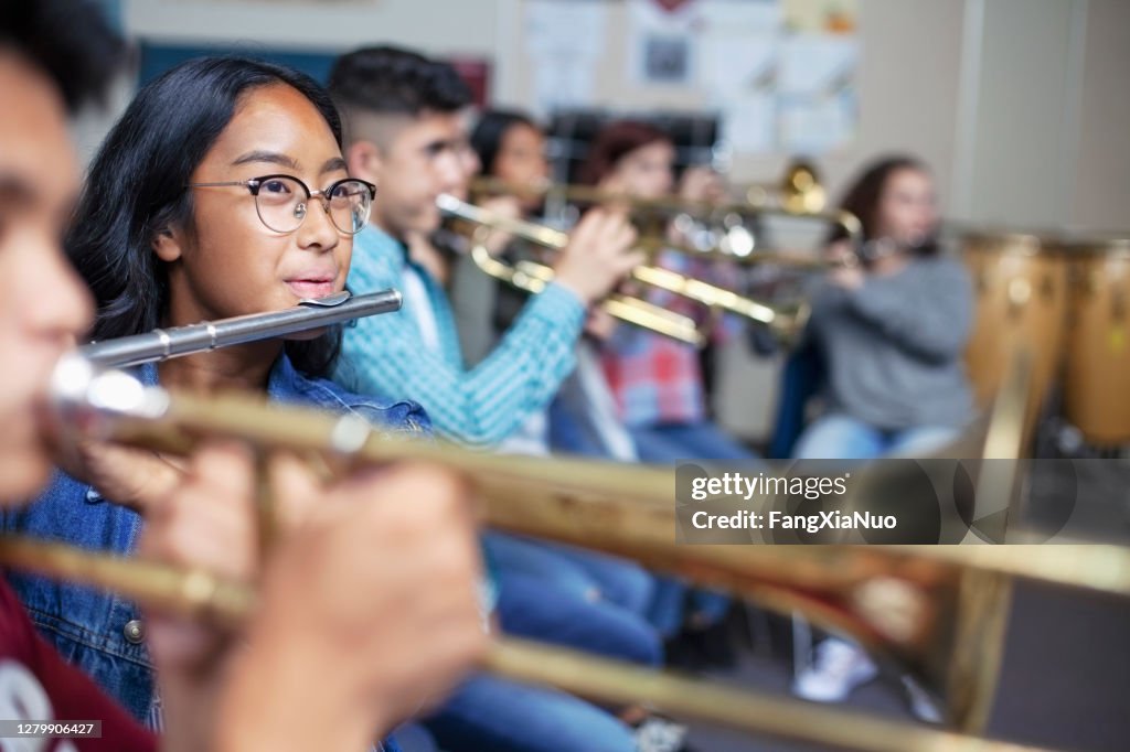 Vertrouwen Gemengde Etnische etniciteit Aziatische tiener die fluit in klaslokaal tijdens orkestbandklasse speelt