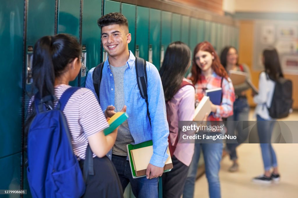 Smiling teenage students talking at high school