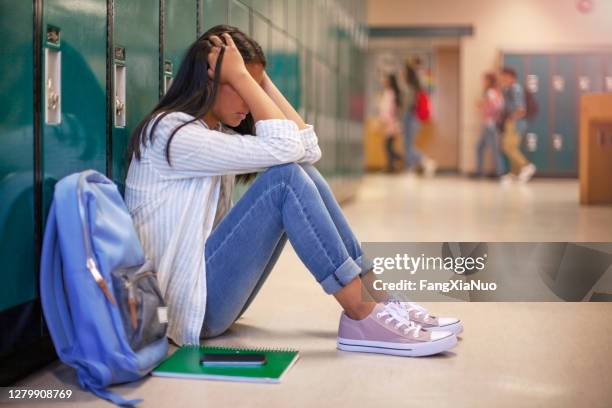 frustrated asian teenage young woman female student with head in hands in hallway in school - bullying stock pictures, royalty-free photos & images