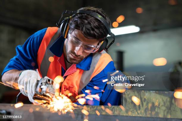 the smart engineer working and wearing protection wear with electric grinder tool on steel structure in factory, sparks flying. - slepen met kabel stockfoto's en -beelden