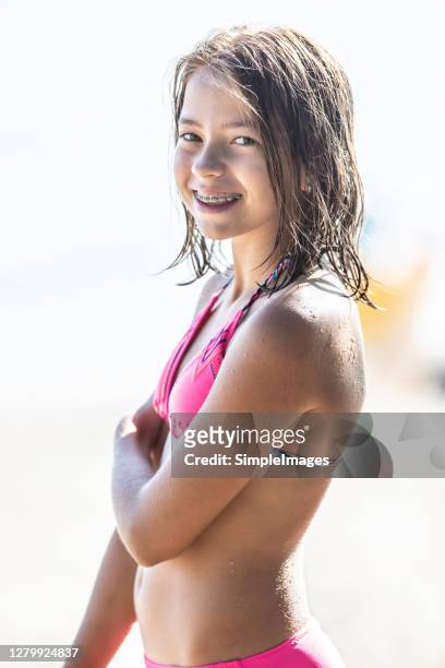 young teenage girl in a swimsuit wearing braces smiles on a beach. - swimsuit models girls stock-fotos und bilder