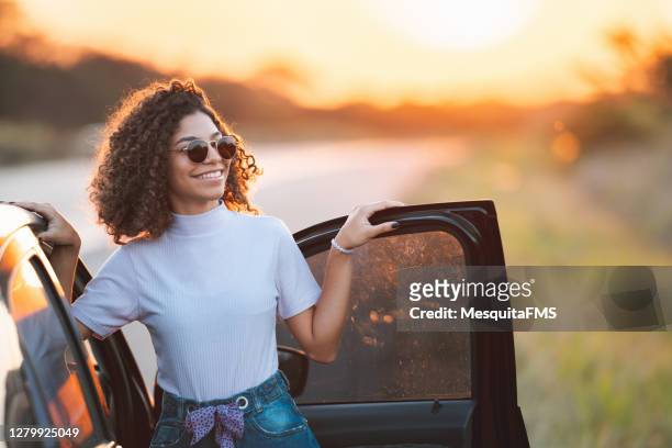 teenager out of the car enjoying the sunset - curls girl silhouette stock pictures, royalty-free photos & images