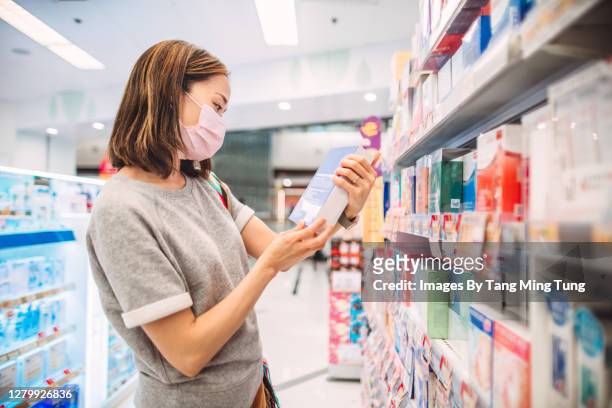 young asian woman with protective face mask shopping for daily necessities in supermarket - face mask beauty product stock pictures, royalty-free photos & images