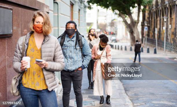 group of diverse people in face masks social distancing on a city sidewalk - social distancing line stock pictures, royalty-free photos & images